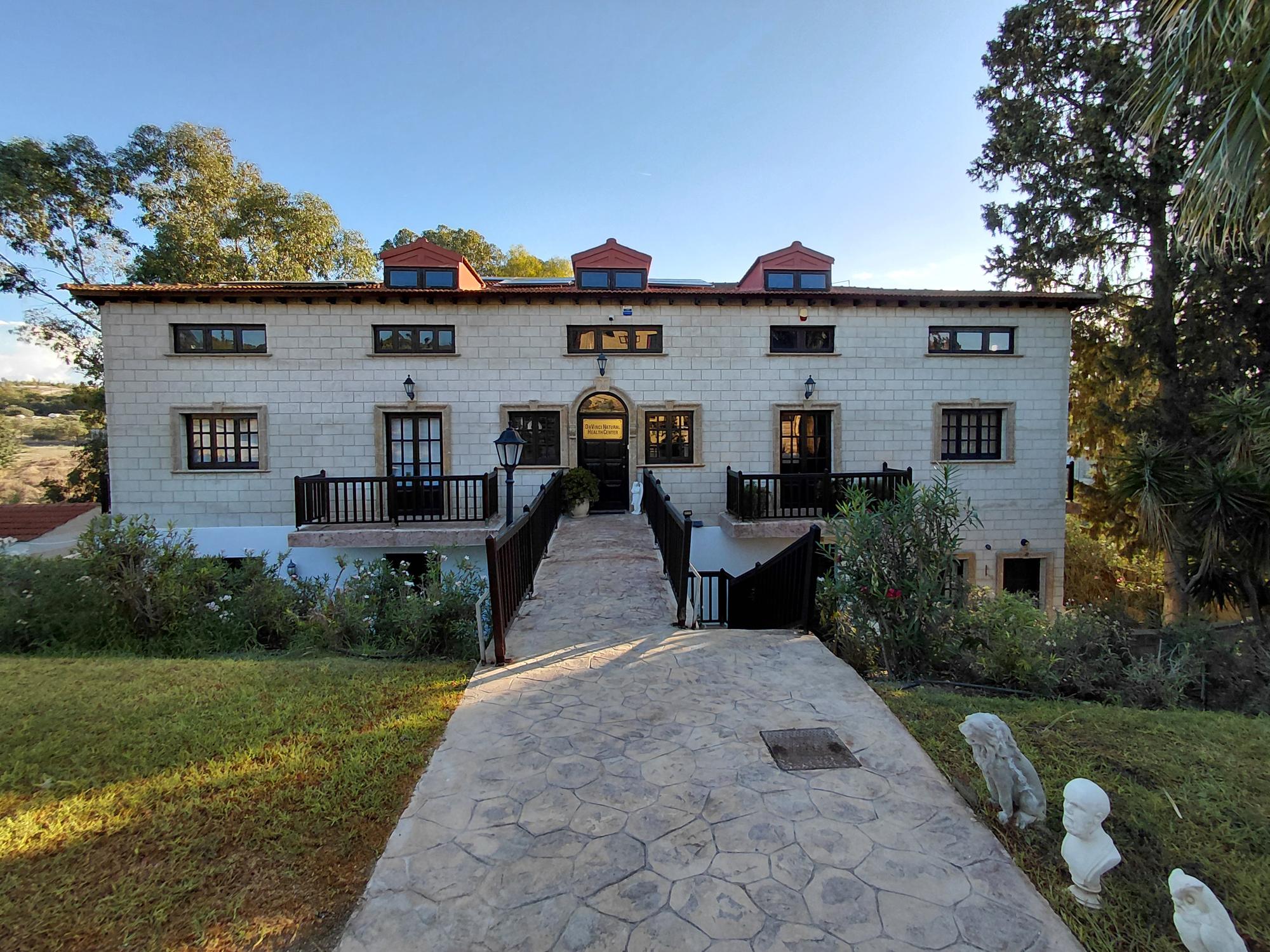 The Da Vinci Holistic Health Centre: a limestone house above a stone path through the gardens in Aradippou, Larnaca